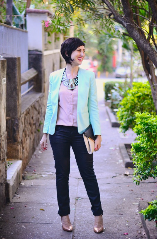 camisa rosa claro, blazer menta, calça preta, scarpin dourado e colar gigantesco de acrílico nas cores preto, rosa e menta