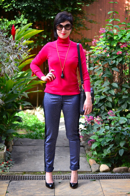 blusa vermelha de tricozinho com gola rolê, calça azul metálico com brocados, scarpin preto e bolsa carteira preta