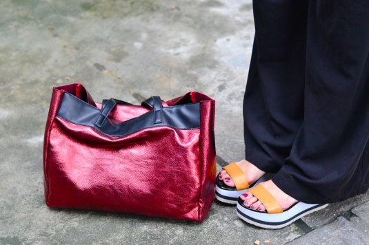 camisa branca sem mangas, colete preto , pantalona preta, sandália flatform solado grosso branco com tiras caramelo, bolsa vermelha metalizada grande