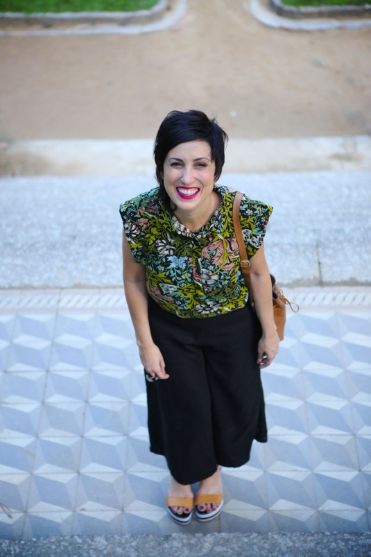 pantalona preta curta, sandlália flat solado grosso branco e tiras caramelo, blusa com mangas japonesas e estampa de folhas verdes, flores rosas e azuis