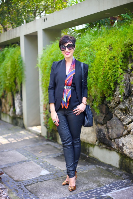 blazer preto, lenço colorido em vermelho, amarelo, azul escuro e azul claro ao longo do pescoço e silhueta arrematado por cinto tressê preto na cintura, tudo por baixo do blazer, calça preta resinada skinny, scarpin de pelos de oncinha e tachas