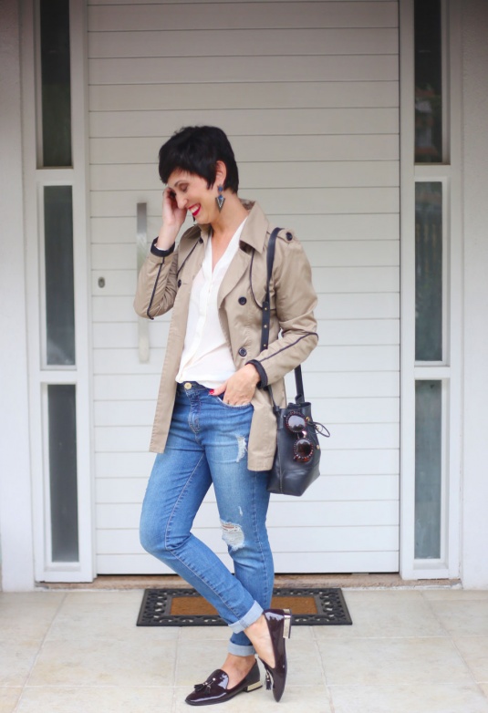 calça jeans lavagem índigo skinny rasgada, camisa branca de seda, trench coat cáqui, mocassim envernizado marrom com tessels