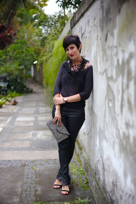 calça skinny preta resinada, blusa preta de manga comprida malha devore, colar felpudo cheio de tentáculos com bolhinhas nas pontas preto, carteira bordada de miçangas prata e sandália duas tiras preta de salto com batom vinho