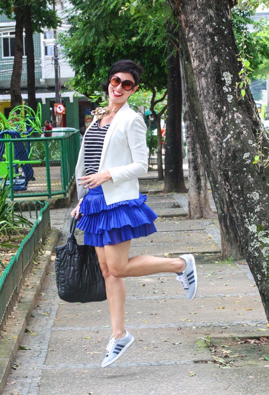 blazer branco, saia azul com babados, camiseta listrada e tênis azul claro