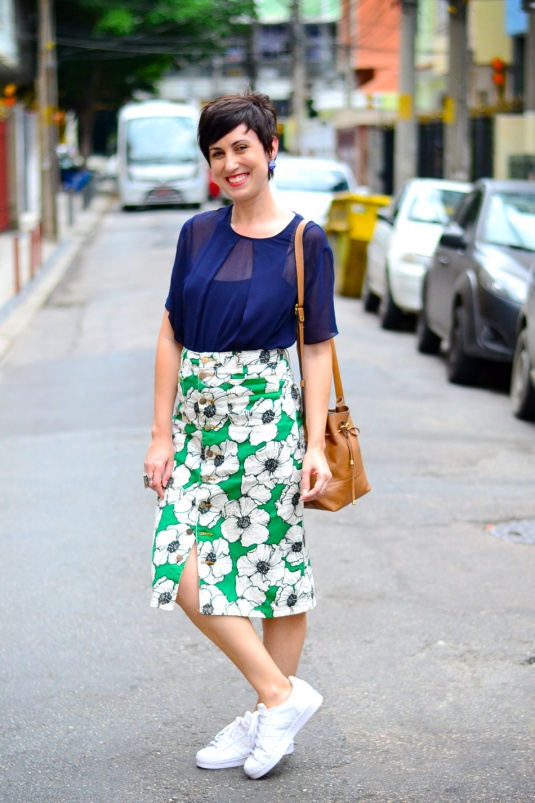 blusa azul marinho meio transparente de seda levinha, saia midi comprida de estampa de fundo verde com flores preto e brancas, tênis branco superstar adidas, bolsa saco caramelo, brincos de resina pequenos azul marinho